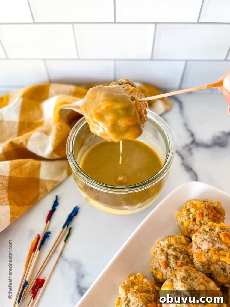 an easy sausage balls being dipped into a sweet hot mustard dipping sauce in a clear weck jar.