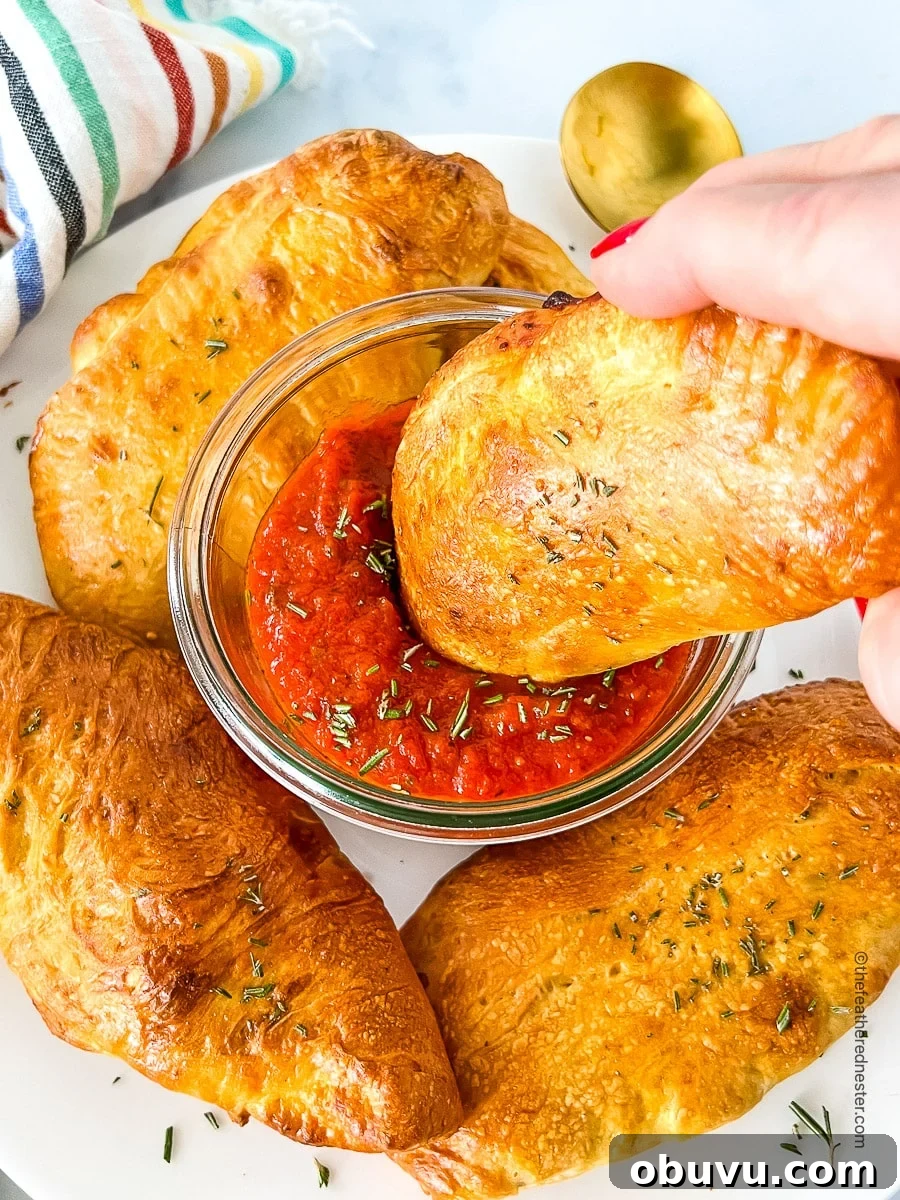 40+ Crowd-Pleasing Finger Food Ideas for Parties and Gatherings 16 a hand dipping a piece of calzone on marinara sauce.