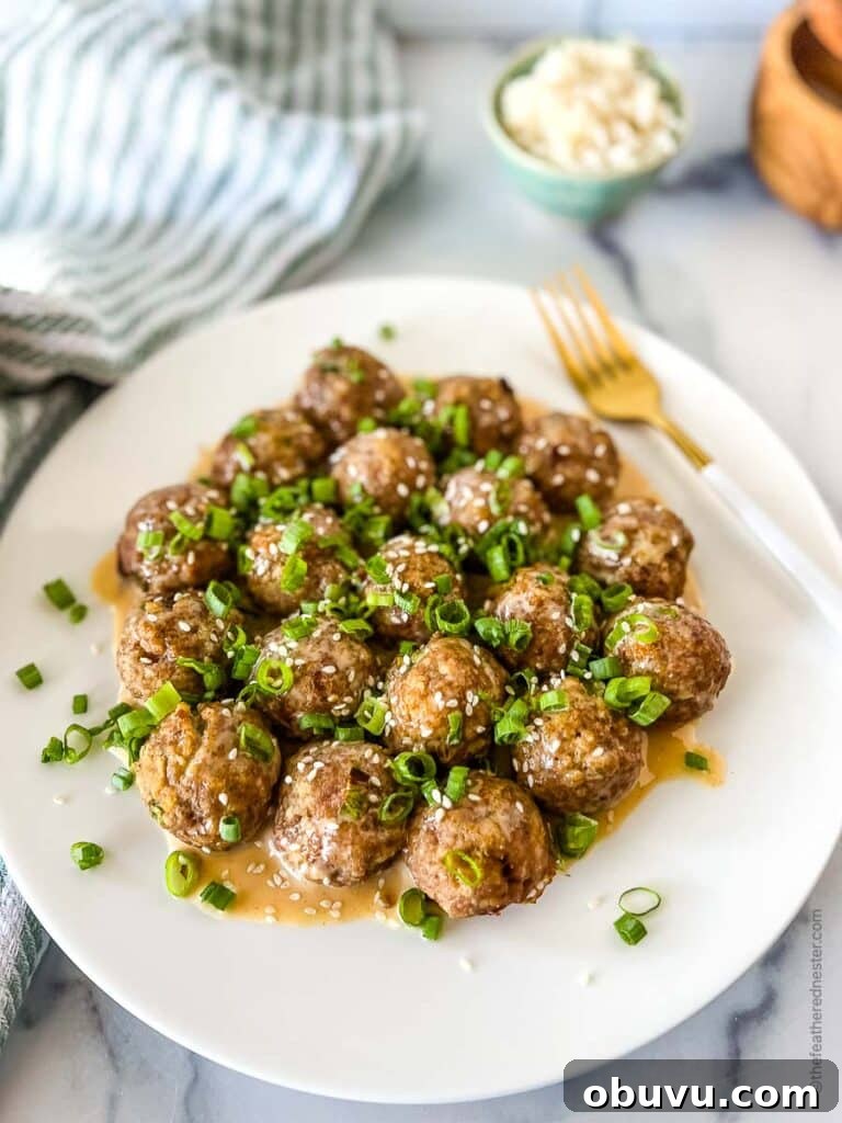 a white platter of honey sriracha meatballs garnished with sesame seeds and green onions.