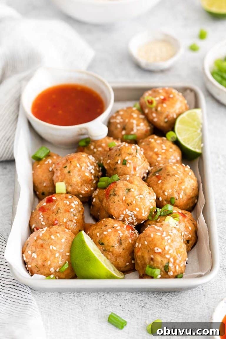 a baking sheet with sweet chili meatballs garnished with cilantro and sesame seeds