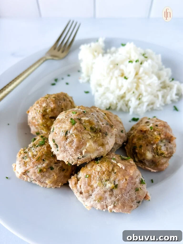 Turkey zucchini meatballs on a white plate next to a fork.