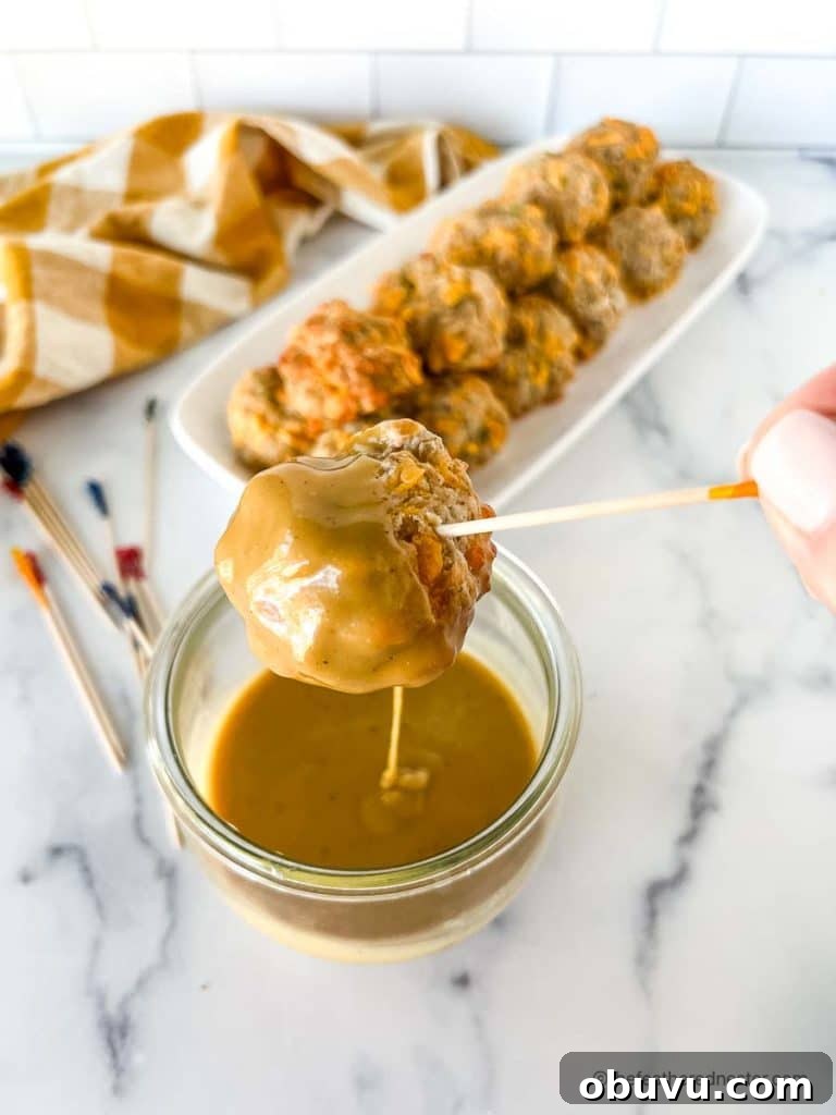 dipping easy sausage balls into a spicy hot mustard sauce in a clear weck jar.