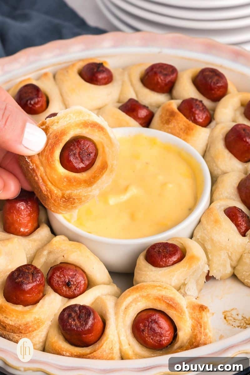 40+ Crowd-Pleasing Finger Food Ideas for Parties and Gatherings 30 A bowl of sauce in the middle of baked pigs in a blanket.