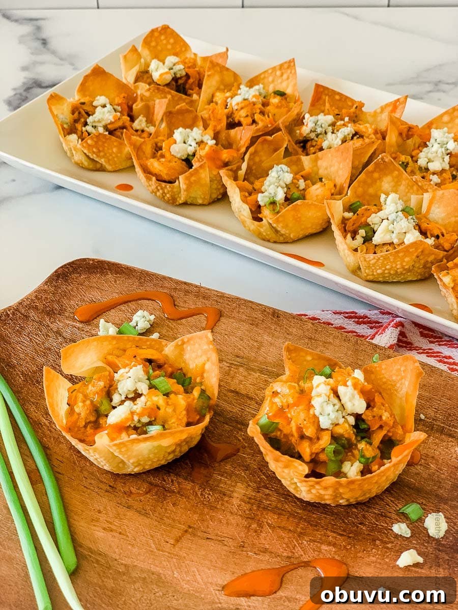 40+ Crowd-Pleasing Finger Food Ideas for Parties and Gatherings 35 buffalo chicken wonton cups placed in a wooden serving tray and white serving plate.