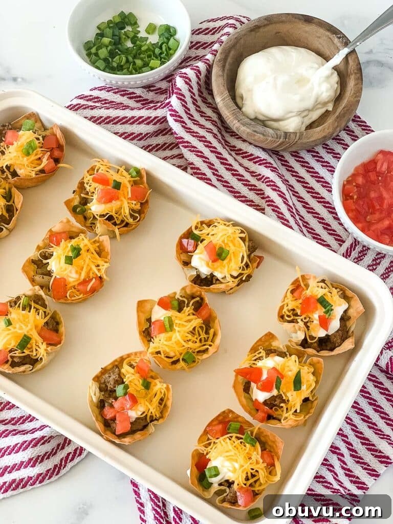 a white tray of taco wonton cups on top of a red and white napkin with bowls of cilantro, sour cream, and salsa.