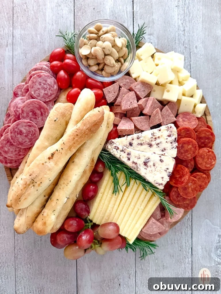 A round charcuterie board mixed with bread, meat, tomatoes, fruits, and cheese.