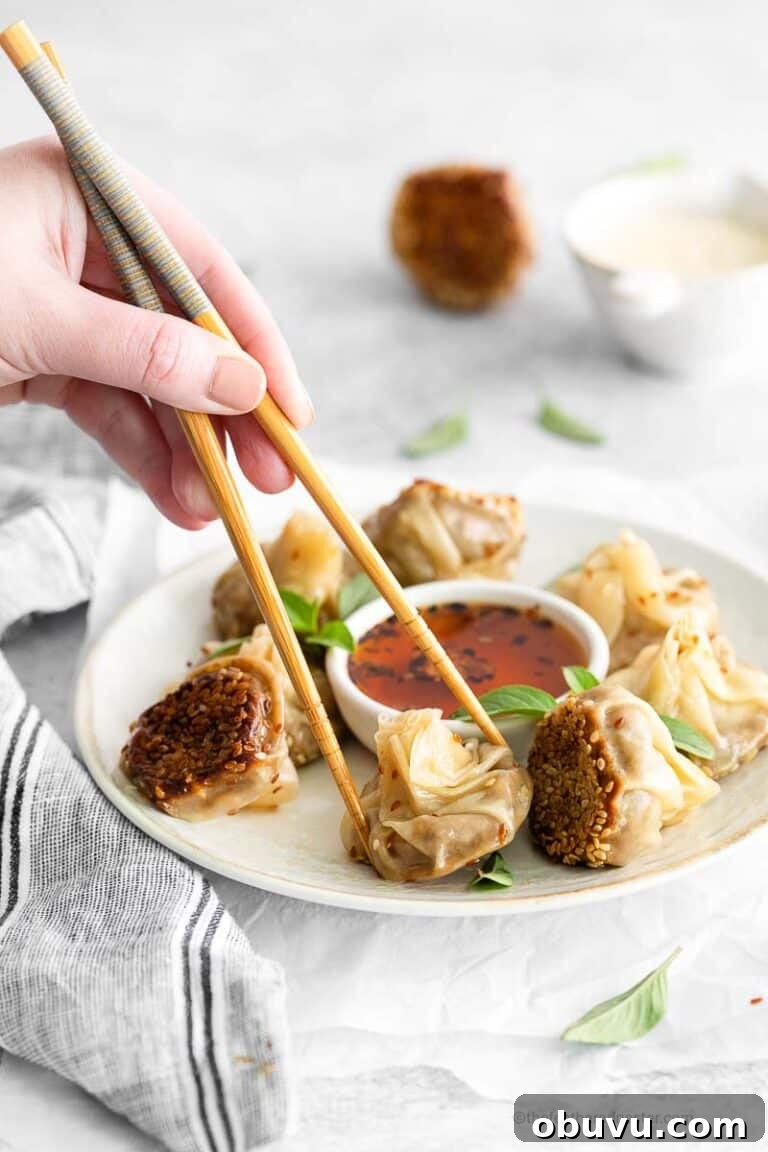 Hand holding filled wonton appetizer in chopsticks.