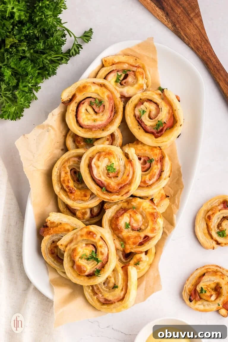 Ham and cheese pinwheels on a white serving platter.