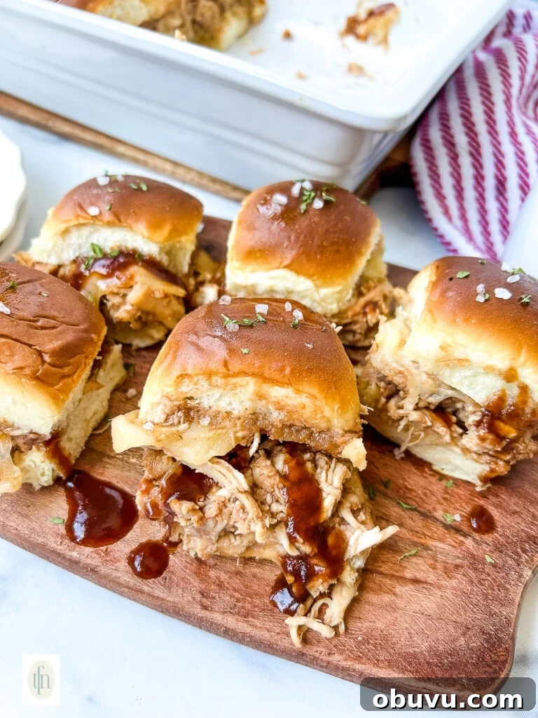 Wooden serving platter filled with shredded BBQ chicken sliders for game day party.