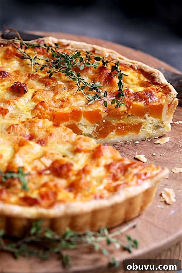 Close-up photo of Butternut Squash Leek and Gruyere Tart with piece removed exposing interior of the tart.