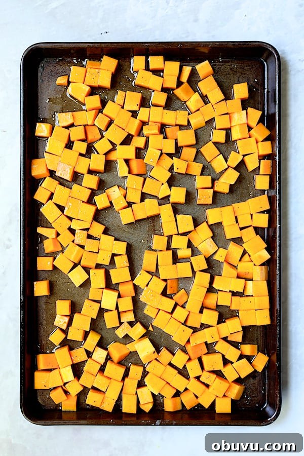 Photo of cubed butternut squash on baking sheet before being roasted.