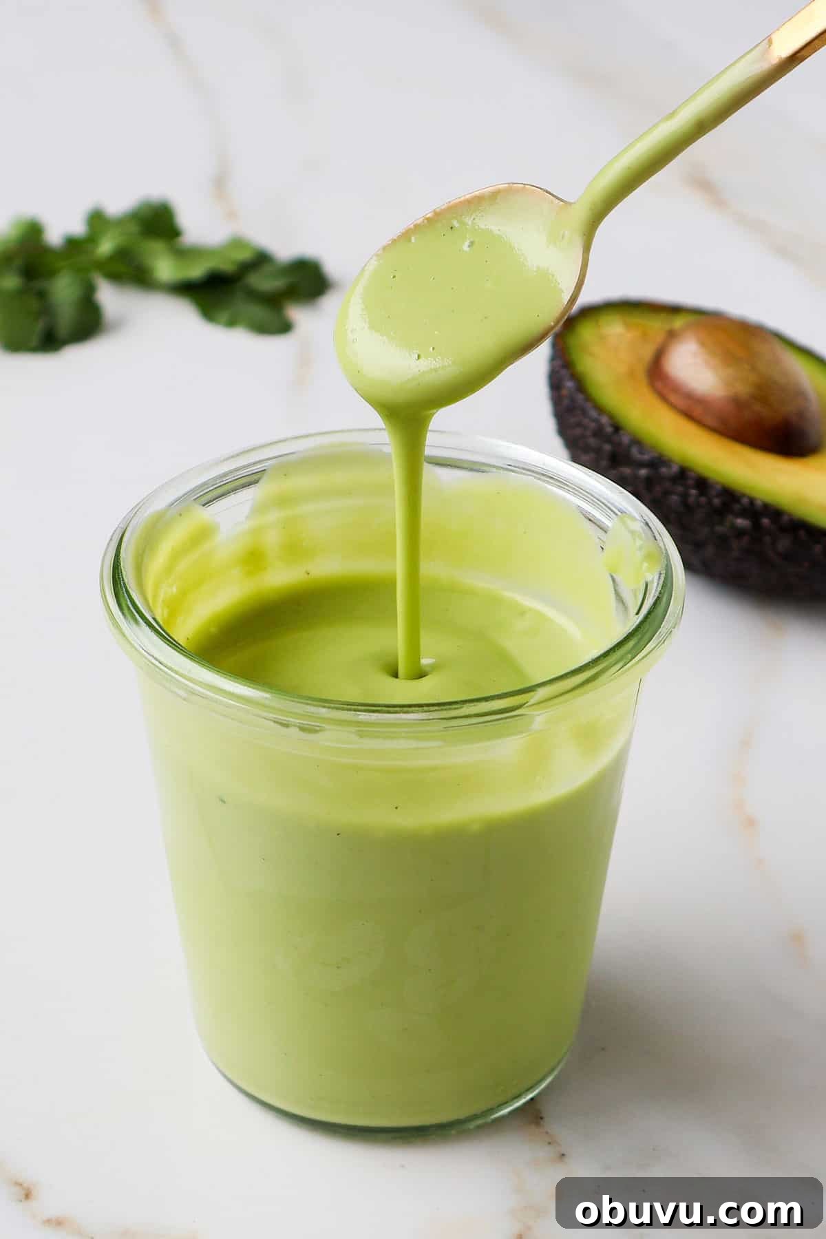 Creamy Avocado Green Goddess Dressing Recipe 3 Avocado dressing poured with a spoon.