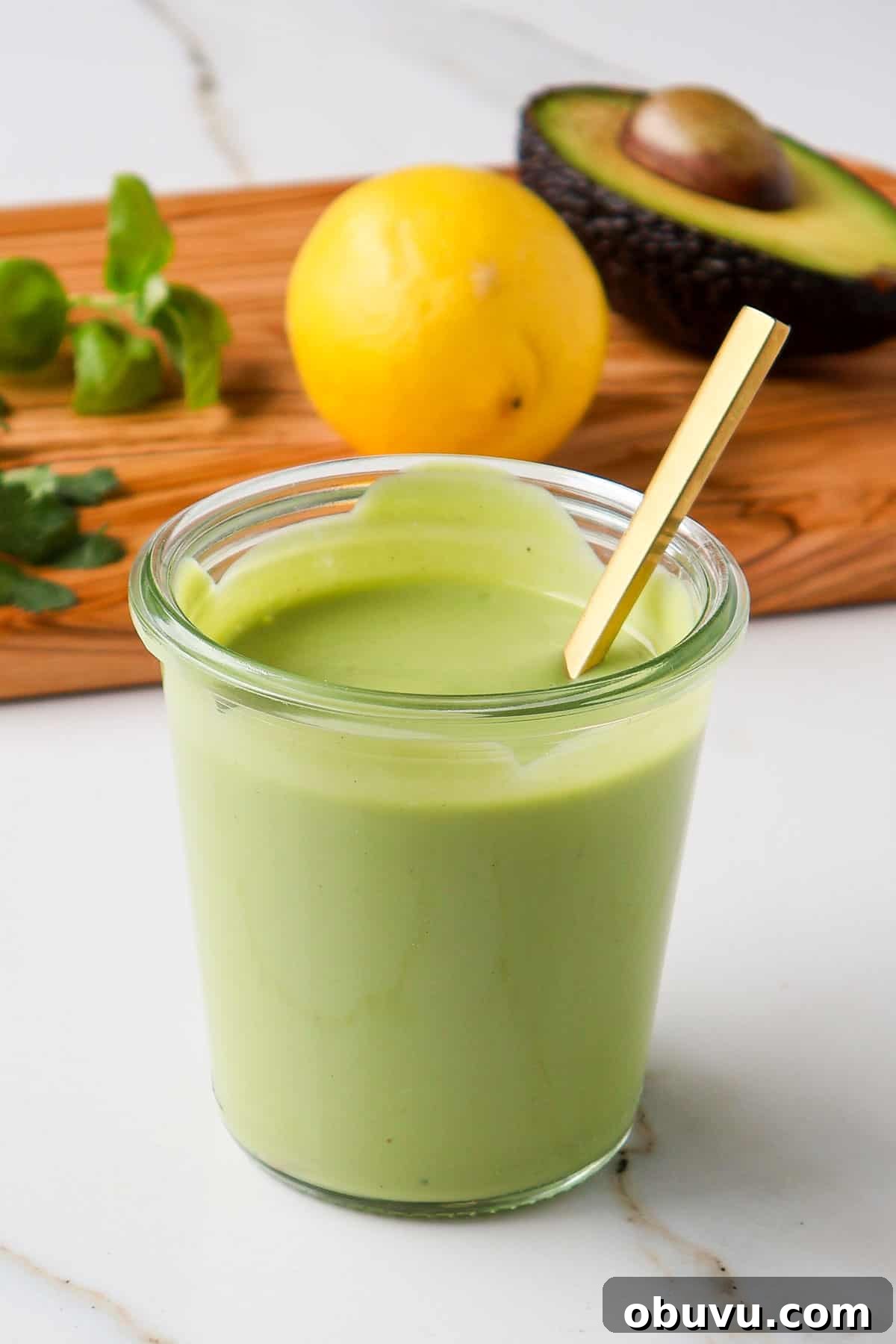Creamy Avocado Green Goddess Dressing Recipe 7 Side shot of dressing in a jar with wood board.
