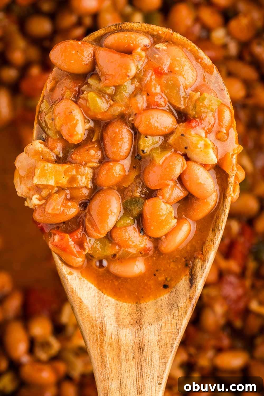 Slow Cooker Charro Beans scooped by wooden spoon