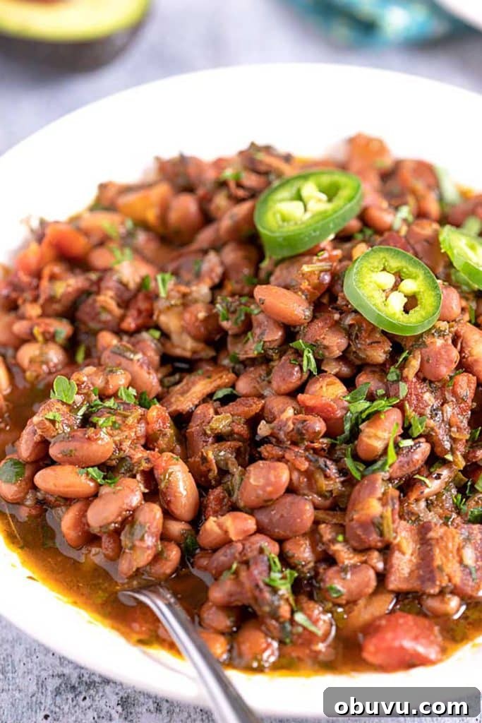 Authentic Charro Beans Recipe (Ranchero Beans) 2 Charro Beans with bacon and cilantro served in a white serving bowl