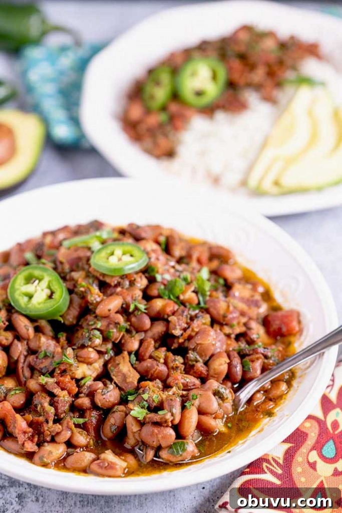 Authentic Charro Beans Recipe (Ranchero Beans) 11 Charro beans in a white bowl topped with jalapeño peppers