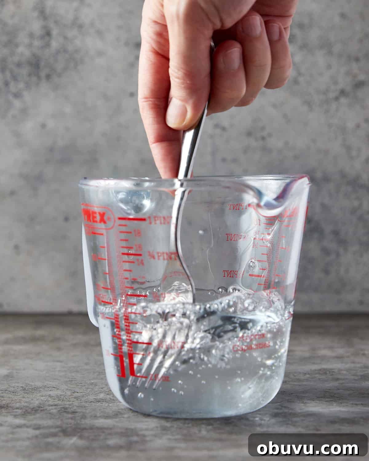 Alcohol-Free Homemade Vanilla Extract Recipe 4 Photo showing someone stirring glycerin and water together with a fork in a jug.