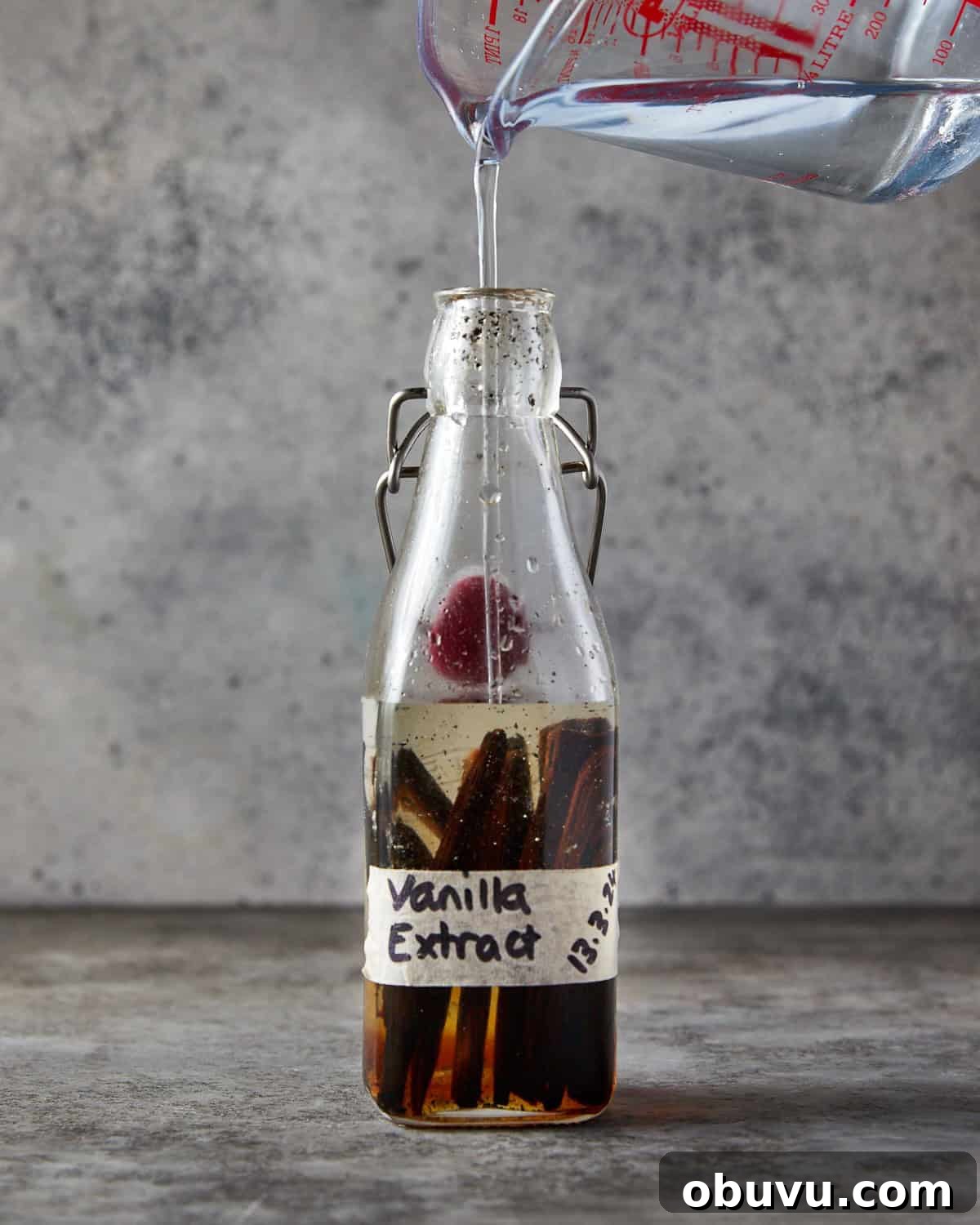 Alcohol-Free Homemade Vanilla Extract Recipe 5 Photo showing vanilla pods in a bottle and the glycerin and water mixture being poured into the bottle with them.