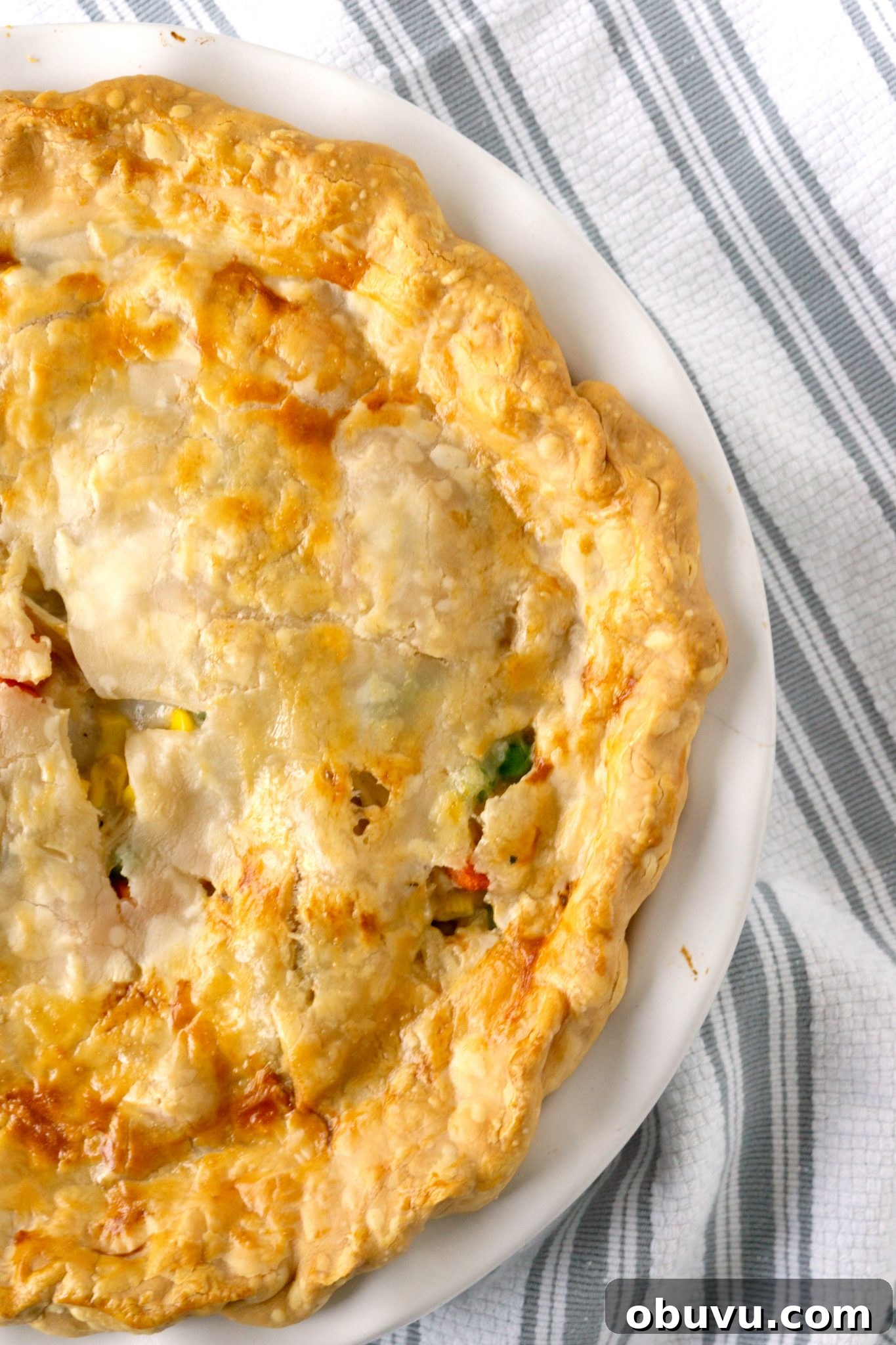 Leftover Turkey Pot Pie Recipe for Comforting Holiday Meals 6 turkey pot pie with pie crust in a white baking dish on a striped towel