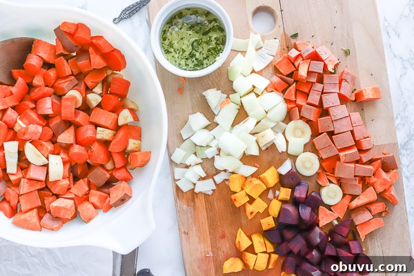 Crispy Roasted Root Vegetables with Herbed Garlic Glaze 3 large bowl of chopped sweet potatoes next to a cutting board full of a variety of root vegetables for roasted root vegetables recipe