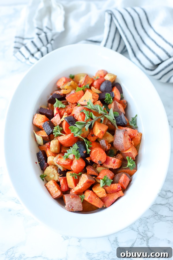 Crispy Roasted Root Vegetables with Herbed Garlic Glaze 5 roasted root vegetables in a white bowl with a black and white stripped towel behind it