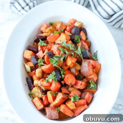roasted root vegetables in a white bowl with a black and white stripped towel behind it