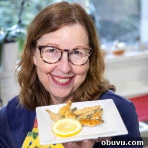 Crispy Keto Fried Sardines: Low-Carb Pan-Fried Recipe 3 Anita holding up Keto Crispy Fried Sardines on a plate with lemon.