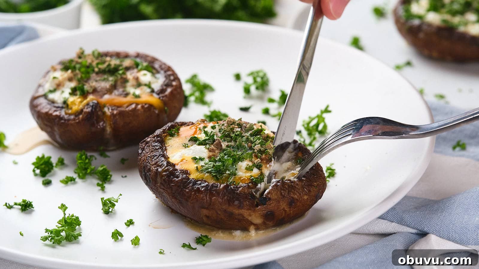 19 Cozy Low-Carb Breakfasts You’ll Crave Every Morning 10 A fork and knife cutting into an egg in mushroom with green garnish visible in the background.