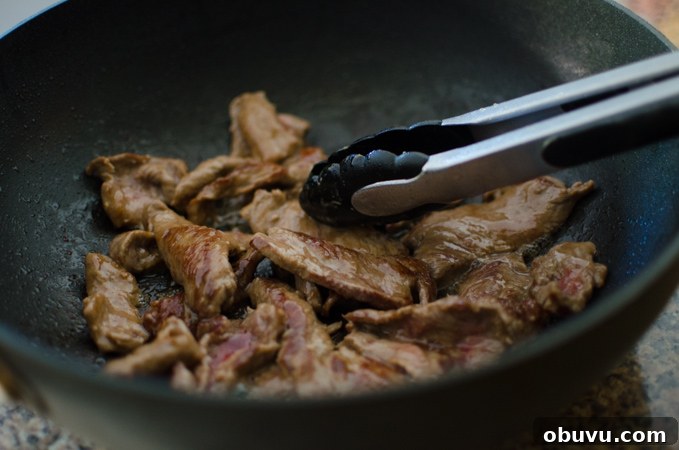 Chinese Beef and Broccoli Stir-Fry Recipe with Savory Sauce 8 Marinated beef quickly stir-fried in a wok with kitchen tongs.