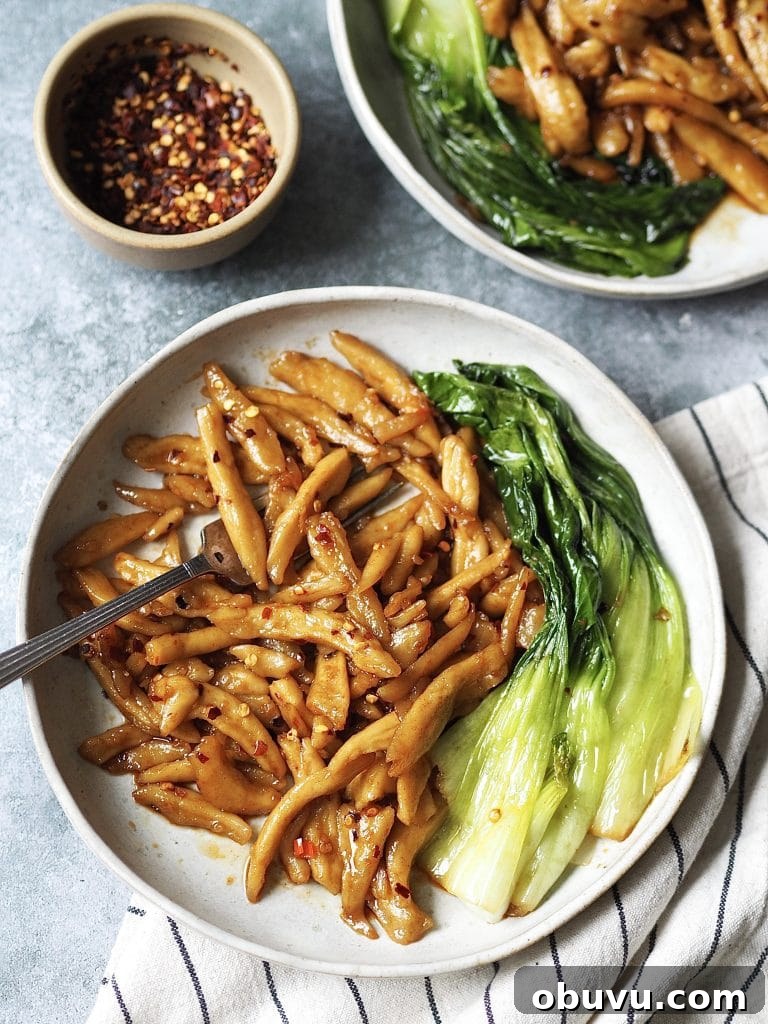 Plate of scissor cut noodles in chilli and garlic oil with pak choi stir fried on the side.