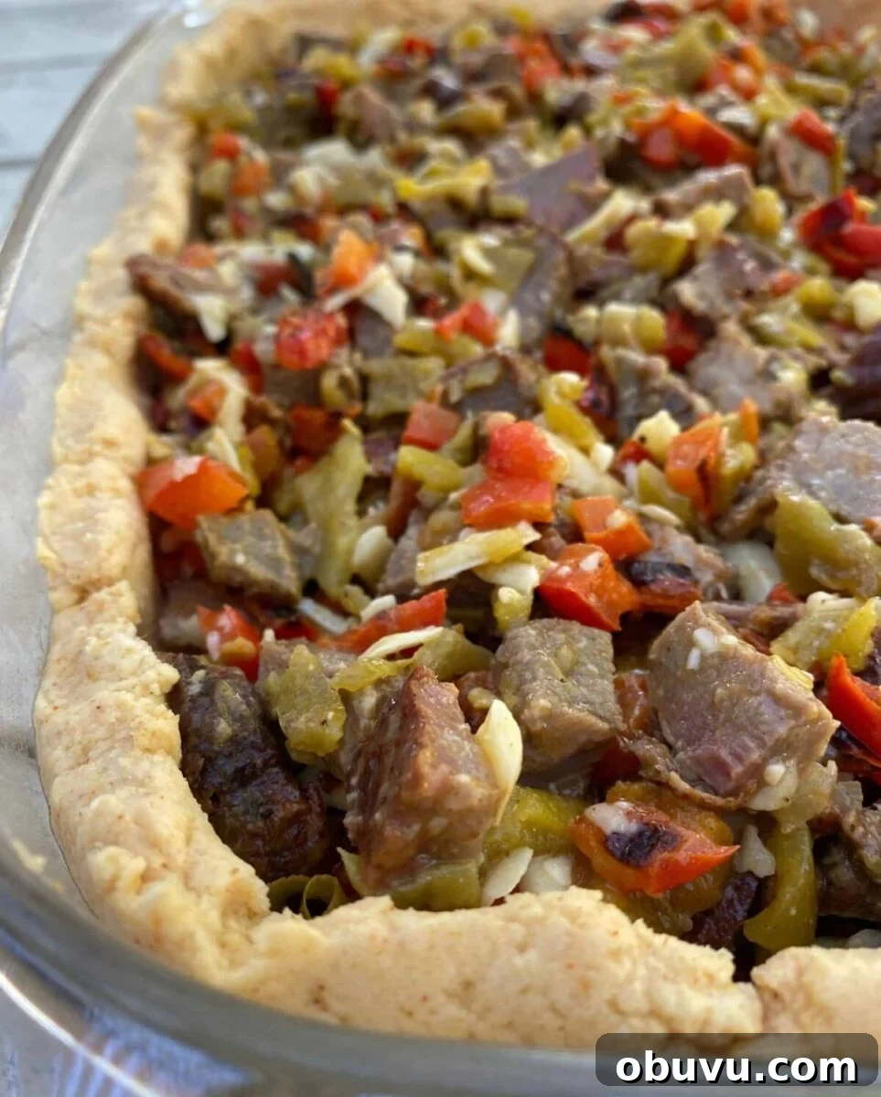 Diced beef with red peppers and green salsa in a tamale crust, all placed in a large glass dish.