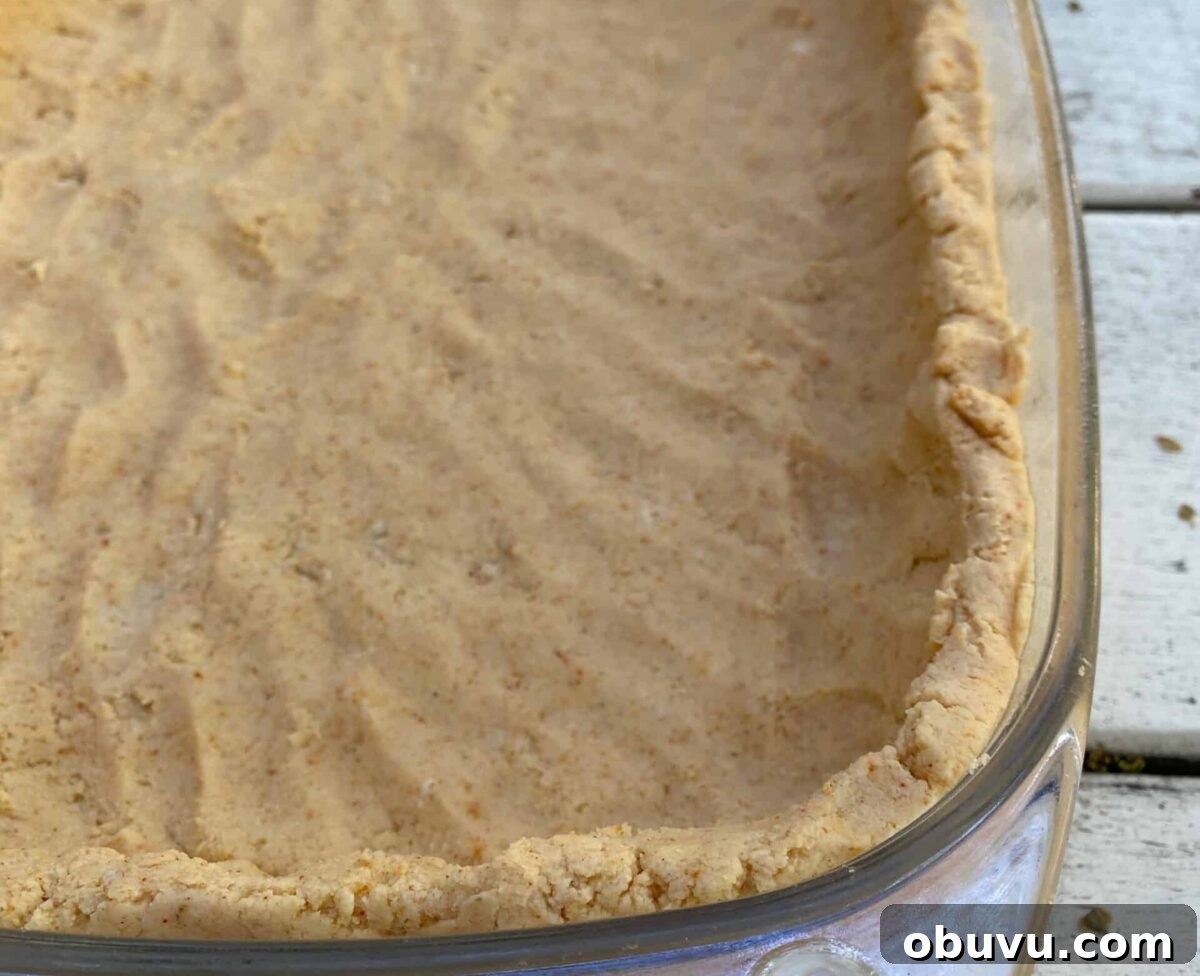 Tamale crust patted into a glass baking dish.