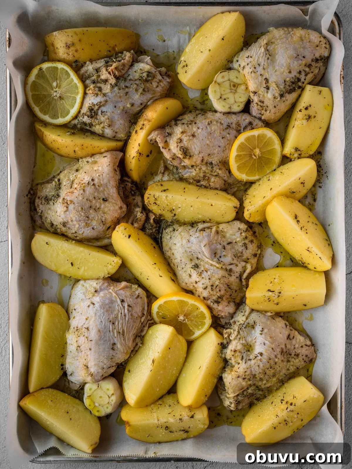 Uncooked Greek lemon chicken and potatoes in a baking tray ready to be roasted.
