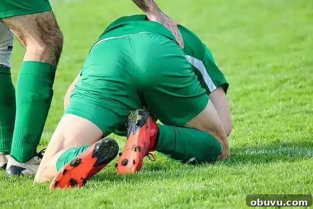 Soccer player kneeling on grass with an injury, possibly