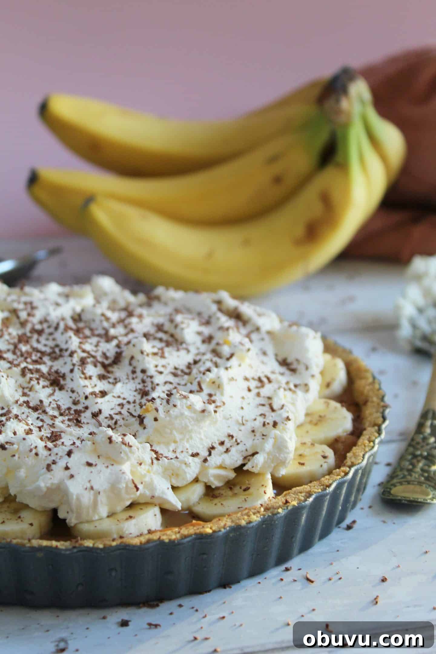 A gluten free banoffee pie with bananas in the background.