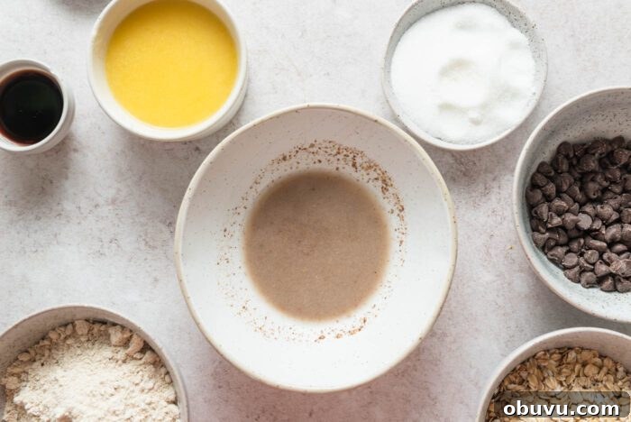 Chocolate chips, oat flour, sugar, rolled oats, vanilla, a flax "egg" and melted butter in small dishes.