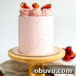 A light pink cake topped with buttercream swirls and strawberry slices