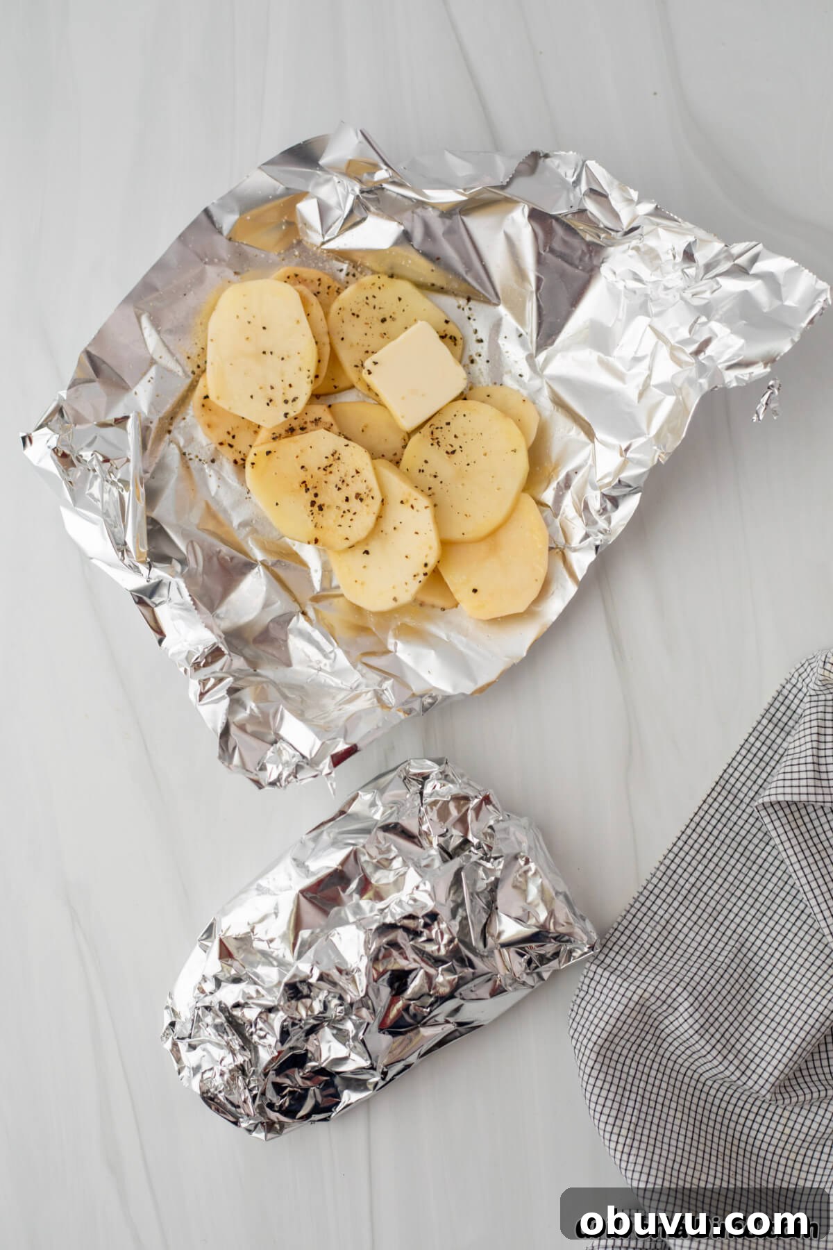 Slice potatoes on a piece of foil topped with pepper and slice butter with a foil packet on the side